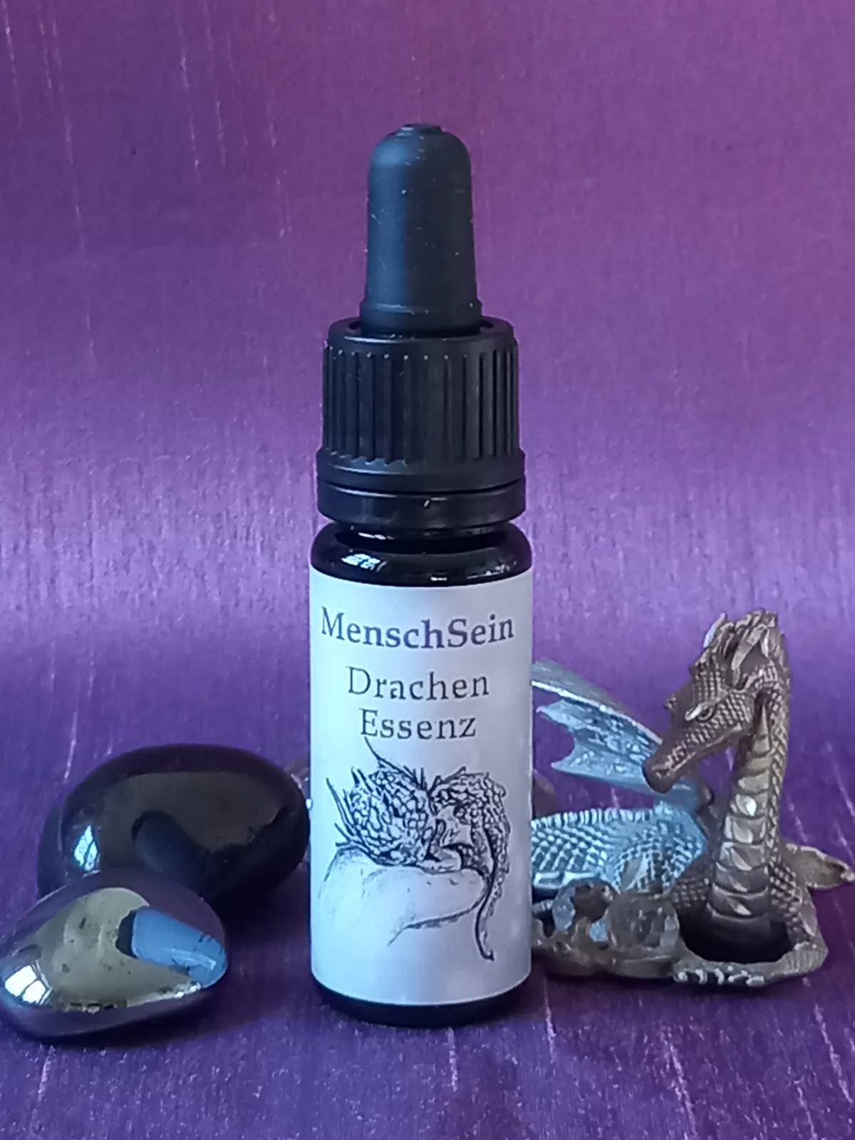 MenschSein Drachen-Essenz mit einer Drachenfigur und dunklen Steinen